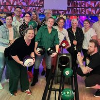 A group of people posing for a photo and holding bowling balls